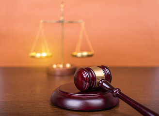 Wooden gavel with scales on wooden table, law concept