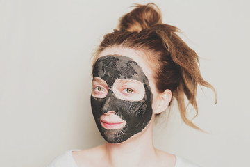 Close-up portrait of attractive girl with a black mask on the face. Skin care.