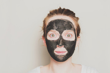 Close-up portrait of attractive girl with a black mask on the face. Skin care.