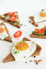 Slices of pie similar to pizza with vegetables, egg and avocado lie on white background, top view.