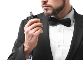 Handsome young man using perfume on white background