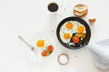 Eating in the process, fried eggs in a frying pan and on a plate, toast with avocado and a cup of coffee for breakfast.