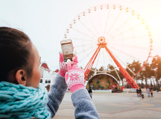 Fototapeta na wymiar Beautiful girl taking picture of a Ferris wheel