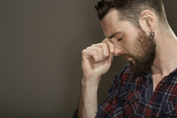 Naklejka premium Words are violence. Cropped shot of a calm bearded guy touching his face thinking with his eyes closed copyspace on the side on dark background.
