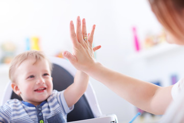 Happy mother playing with baby boy at home