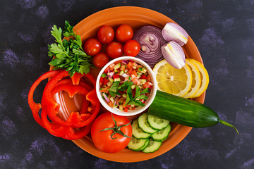 Salsa with ingredients on dark background. Top view