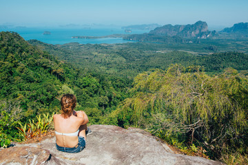 Girl sitting on the view poinf of the mountain. Trvelet enjoing the landscape from mountain