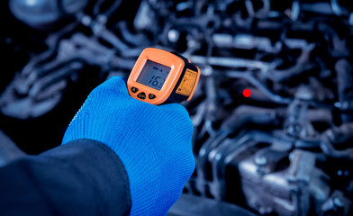 infrared laser thermometer in hand. Motor temperature measurement
