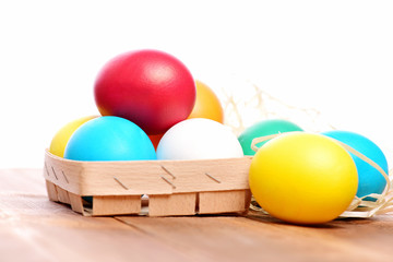 easter colorful eggs in wooden basket with straw nest