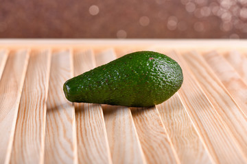 fresh green avocado on brown wooden table, sparkling background