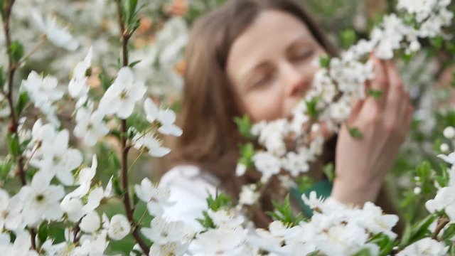 outdoor portrait of a beautiful woman in white jacket among white blossom tree