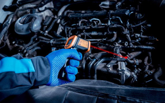 infrared laser thermometer in hand. Motor temperature measurement