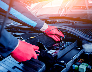 transportation, winter and vehicle concept - closeup of man under bonnet with starter cables