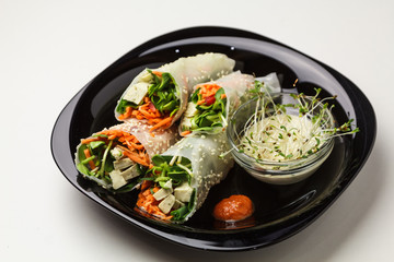 Beautiful view of a plate of spring rolls with sweet chili sauce; styled on black plate