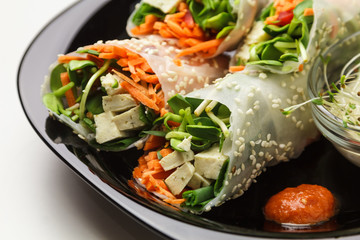 Beautiful view of a plate of spring rolls with sweet chili sauce; styled on black plate