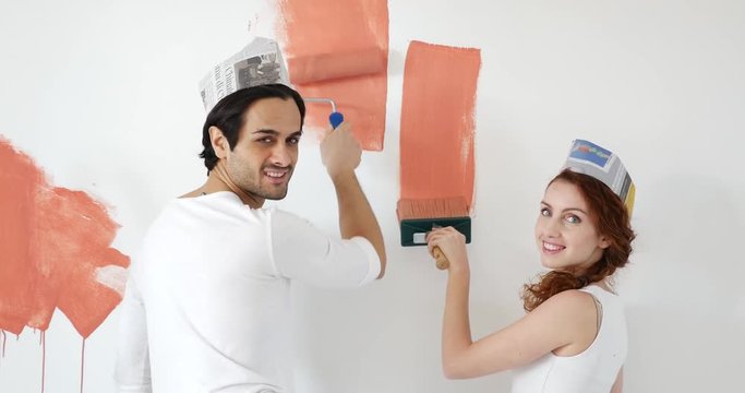 Happy couple renovating home. Painting the walls in red