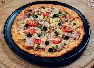 Large hot pizza on the black plate.