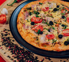 Large hot pizza on the black plate.