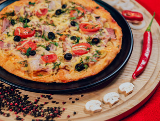 Large hot pizza on the black plate.