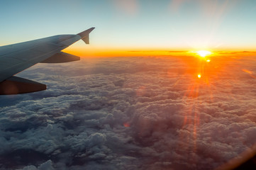 Fototapeta premium sunset from the window above the clouds with airplane wing