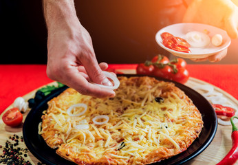 The cook is making pizza. Adds the ingredients.