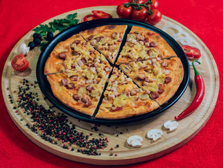 Large hot pizza on the black plate.