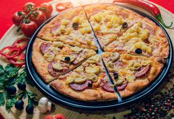 Large hot pizza on the black plate.