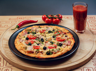 Large hot pizza on the black plate.