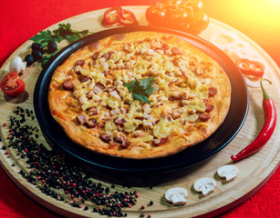 Large hot pizza on the black plate.
