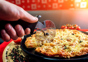 The cook is making pizza. He puts the cheese. Cut pizza into pieces.