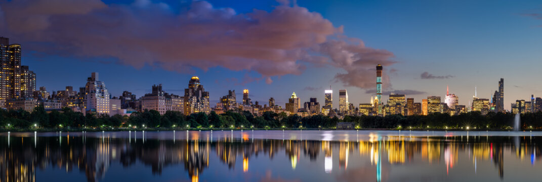 Panoramic view of the Central Park Reservoir and Midtown skyscrapers illuminated at twilight in Summer. Manhattan, New York City