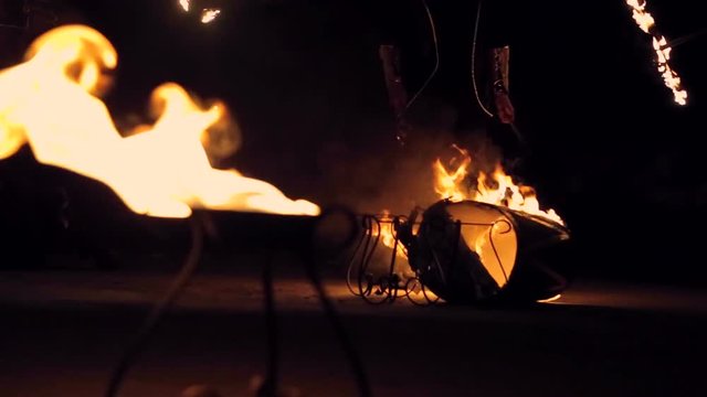 Man plays burning drum. Against the backdrop of flashing lights. Drum burnt artist finishes drum which burns