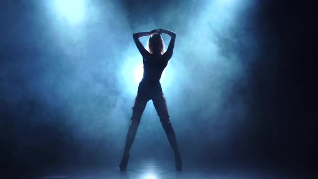 Blonde showgirl in leather lingerie dances, smoky background, slow motion
