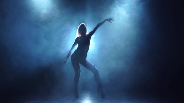 Seminude female dancer in swordbelt underclothes. Smoky background, slow motion