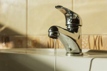 stream flows from a poorly closed faucet. Waste of water