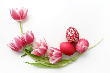 Easter eggs and tulips on white background. Flat lay. Top view