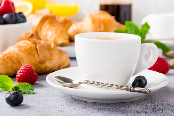 White cups of coffee and croissants on light gray background, selective focus. Healthy breakfast concept with copy space.