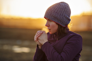 A girl in sports clothes breathes in the palm of her hand trying to keep warm