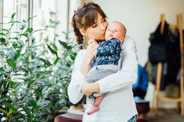 Mother kissing cute newborn son. Parenthood, love and happiness concept.