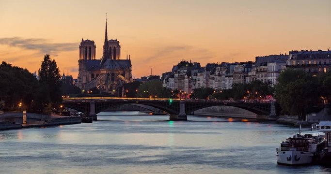 Notre Dame de Paris Cathedral, Ile Saint Louis and the Seine River at twilight. Time lapse of a summer evening with illuminating city lights in the 4th Arrondissement of Paris. France
