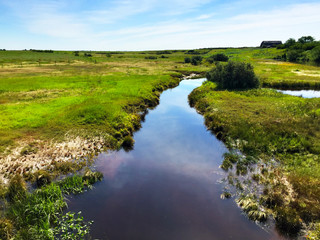 Fototapeta na wymiar Rural prairie landscape with a boggy creek running through marsh land in summer.