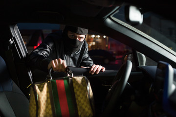 Male thief steals bag from car on parking