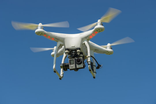 quadrocopter with the camera in flight against a blue sky