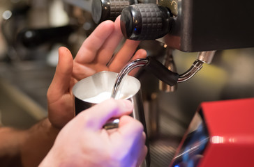 Barista preparing milk for takeaway coffee. Close-up view on hands, barista coffee preparation service concept