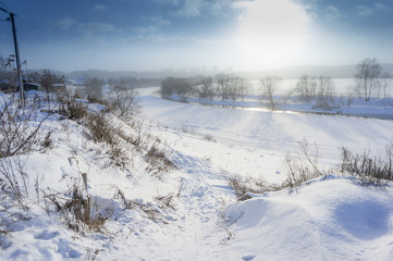 beautiful winter rural landscape with river, steep bank, trees and snow