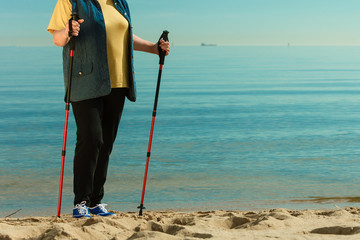 Senior woman practicing nordic walking on beach