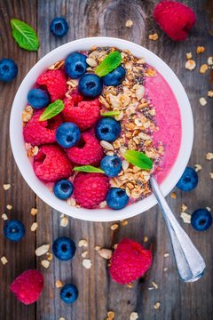 Breakfast smoothie bowl  with granola, fresh raspberry, blueberry, chia seeds and mint