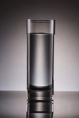 Glass of water with reflection and gradient background - product concept