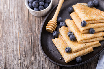 Crepes with honey on wooden background