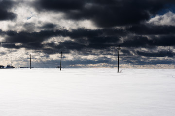 field of snow with electric poles and cloudy sky